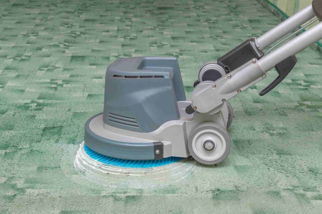 A person is engaged in cleaning a carpet with a machine, showcasing the process in a clean and organized space.