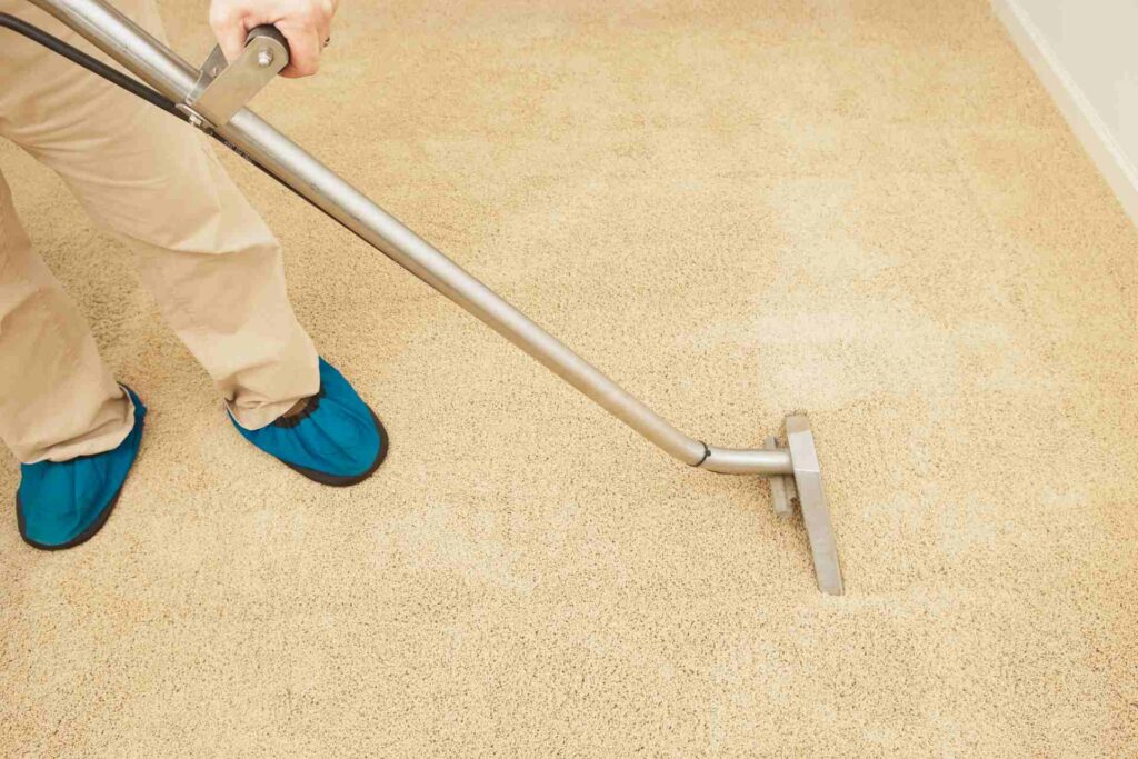 A person operates a vacuum cleaner on a carpet, effectively removing dirt and debris from the surface.