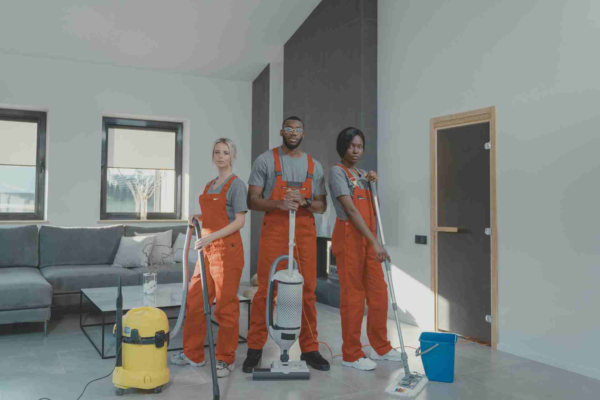 Three workers in overalls focused on cleaning a room, highlighting their commitment to maintaining a tidy environment.