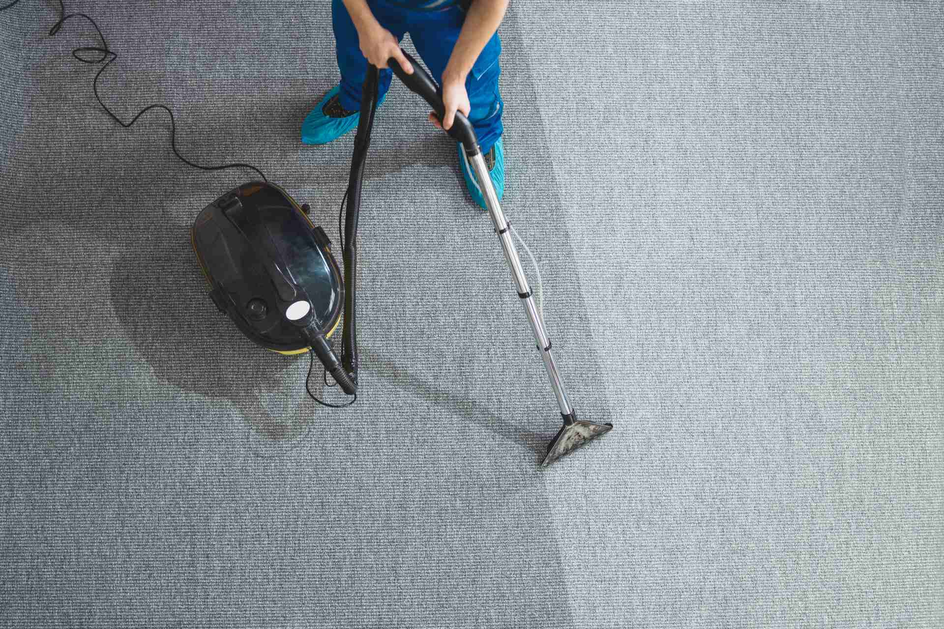 A person using a vacuum cleaner to clean a carpet, demonstrating effective home maintenance and cleanliness.