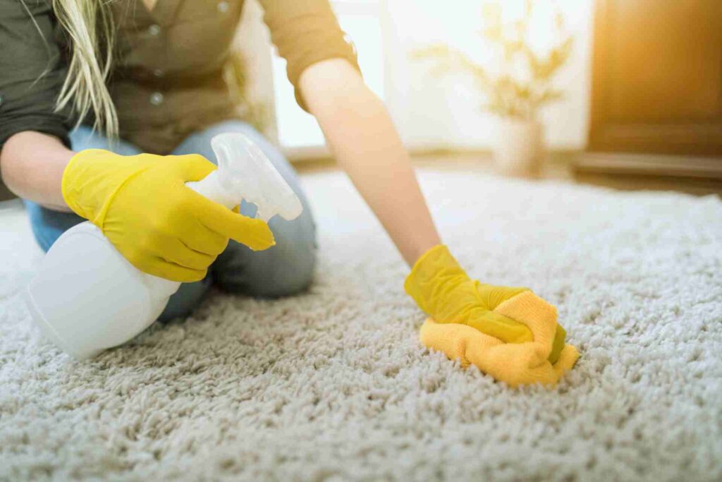 A woman wearing a yellow glove cleans a carpet, demonstrating effective household maintenance and care.