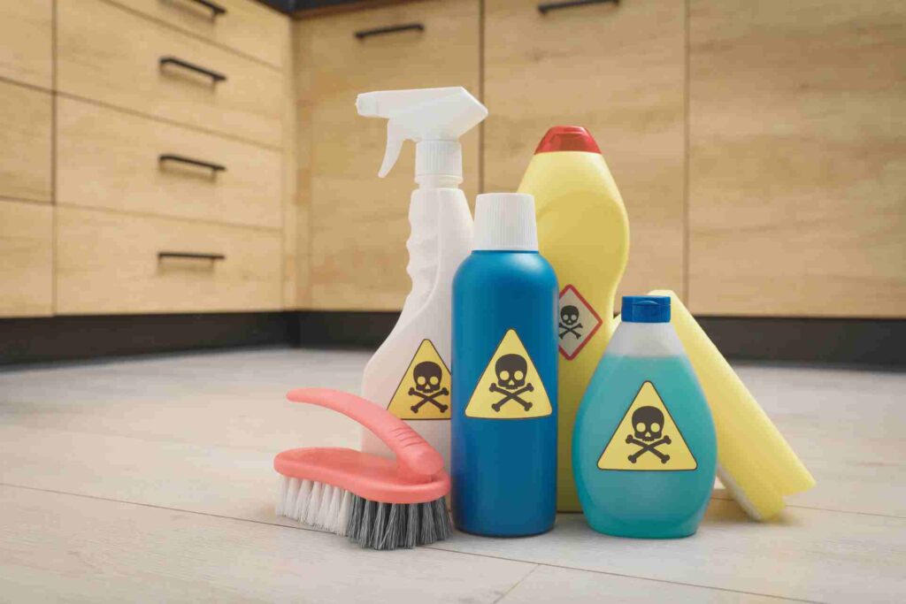 Cleaning products containing harsh chemicals arranged on the kitchen floor, emphasizing safety and proper practices.