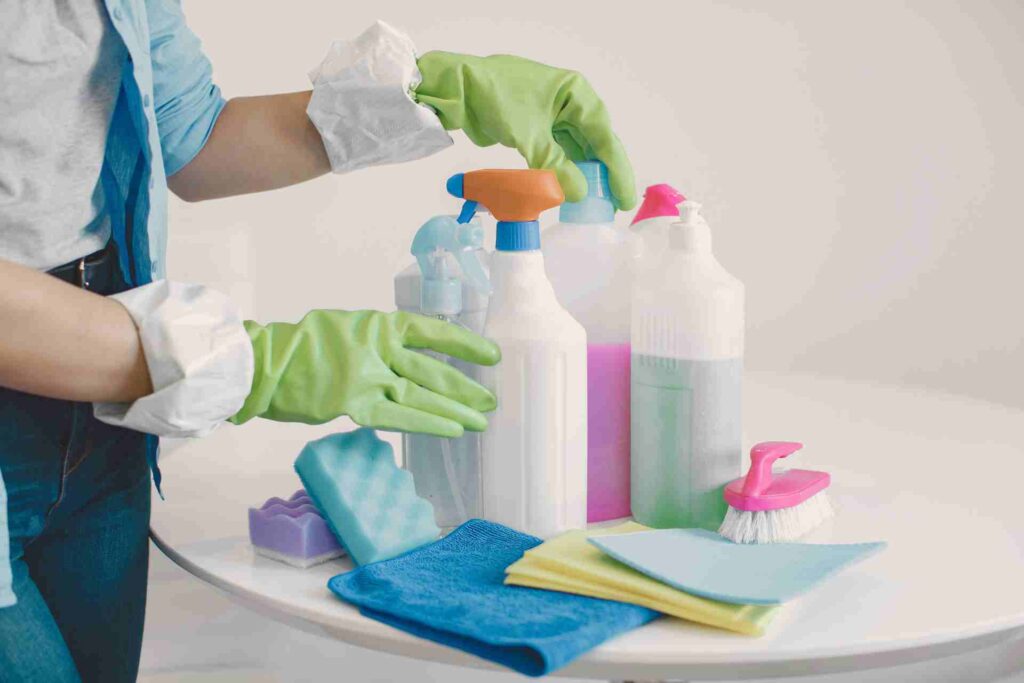 A person in gloves using cleaning products to sanitize a surface, demonstrating effective cleaning practices.