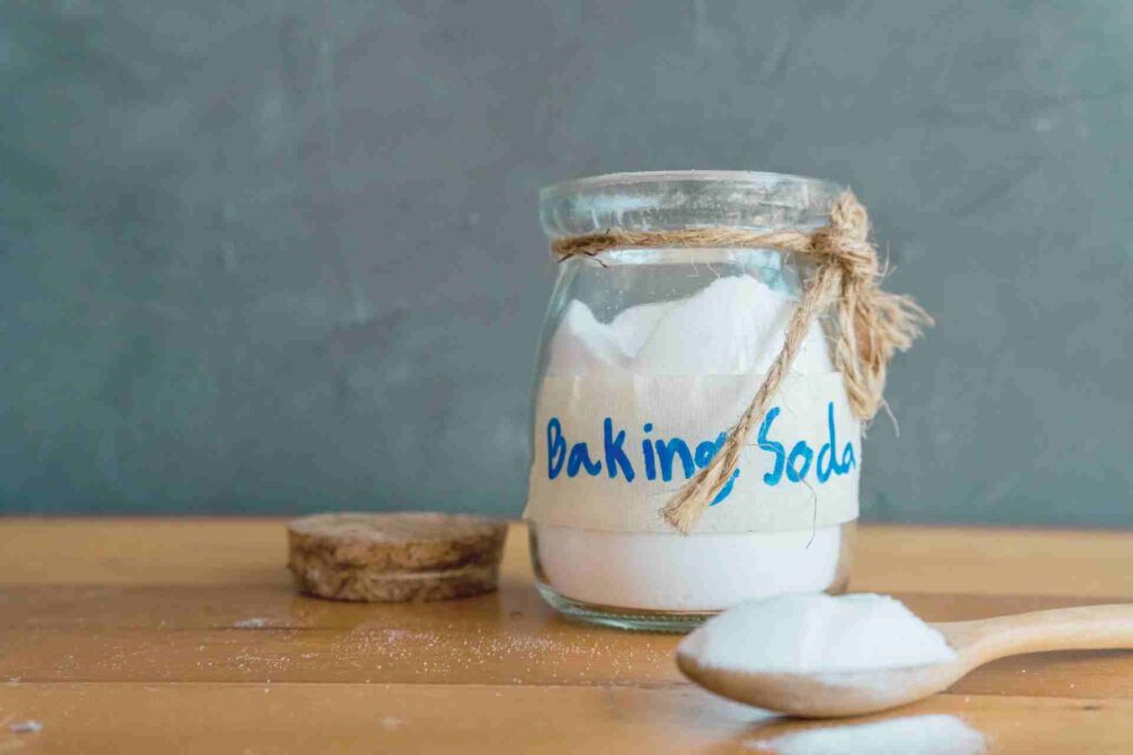 Baking soda in a glass jar with a spoon resting beside it.