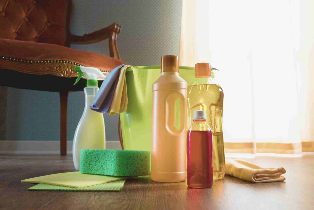 Cleaning products arranged on a floor, showcasing a variety of bottles and tools for household cleaning tasks.