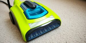 Modern portable carpet cleaner on a clean carpet background.